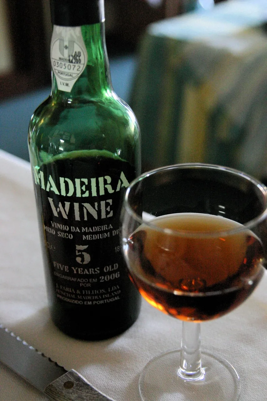 A bottle and glass of Madeira wine; an illustration of the wine style, not a recommendation of the label.